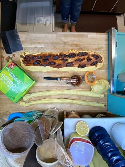 An overhead view of a countertop, with a portion of dough rolled out into a rectangle and filled with apple butter and dates.
