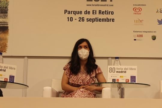 Sonia Lerones mira hacia arriba mientras sus brazos descansan sobre su regazo. Está sentada con las piernas cruzadas sobre un sillón individual blanco. Lleva mascarilla. A la derecha hay una mesa cristal redonda.