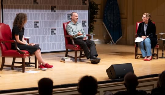 Three people on stage in red chairs