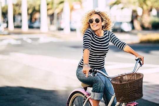 Beautiful and cheerful adult young woman enjoy bike ride in sunny urban outdoor leisure activity in the city