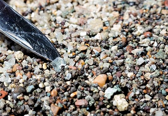 Close up of a lifting a piece of clear stone out of many tiny pebbles. Diamond hunting at Crater of Diamonds State Park.