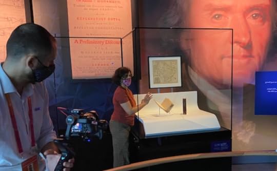 The Jefferson Koran, enclosed in a large plexglass case, in front of wall displays of a painting of Jefferson and blown-up copies of the Koran's title pages