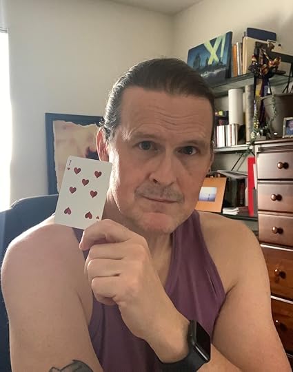 A white male (me) holding a playing card, specifically the seven of hearts.