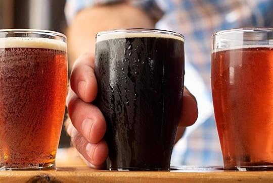 Selection of amber and dark beers and someone reaching for the dark beer at Penn Cove Brewing