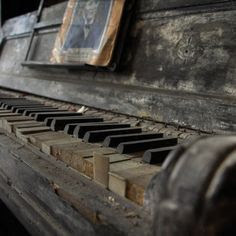 An old disused dusty close up shot of a piano keys, with a photo of someone on the music sheet stand