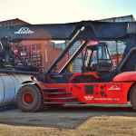 red and black front loader beside intermodal containers