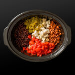 adding the beans, chiles, tomatoes, and pork and onion mixture to the crockpot.