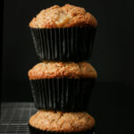 vegan muffins in black muffin papers stacked on top in a single stack.