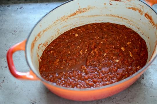 Angled view of cooked harissa. It's mostly red, with chunks of white garlic showing through.