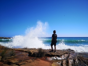 Boy looking at rough see on sunny day