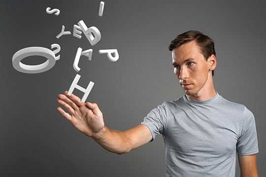 A man in a gray shirt against a gray background waves his hand at some white three-dimensional letters that are floating in front of him in a random cloud of letters. Dyslexia and the visual brain.