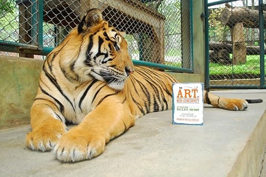 Image: a tiger in an enclosure, looking at a paperback book standing nearby.