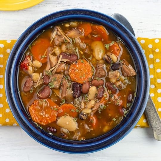A blue bowl filled with turkey and bean soup.