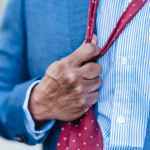 unrecognizable worker loosening tie on street