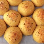 pumpkin dinner rolls risen and baked on parchment with everything seasoning.
