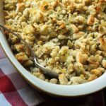 close up of spoonful of stuffing being scooped from baking dish.