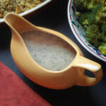 mushroom and onion gravy in a yellow gravy boat on the dinner table.