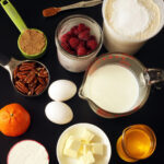 baking ingredients in measuring cups laid out on black table.