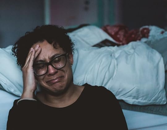 woman crying at the foot of her bed