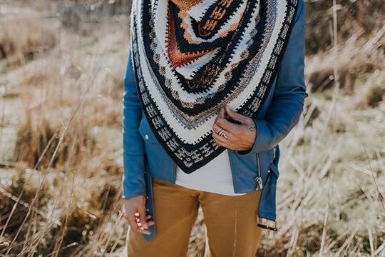 Woman standing wearing knit shawl.