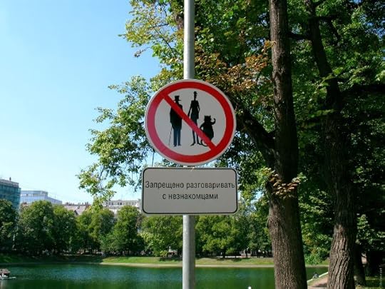 Street sign on a light post, featuring silhouettes of Woland, Behemoth, and Koroviev overlaid with a 'forbidden' crossbar