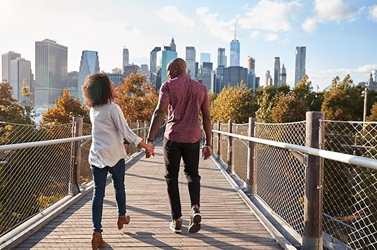 Couple walking on decked area with New York skyline in the background 