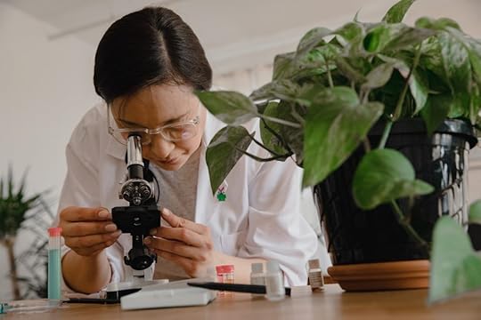 a girl is lookin at the sample through a microscope