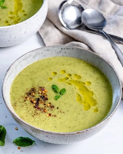 white bowl of zucchini basil soup with a white background