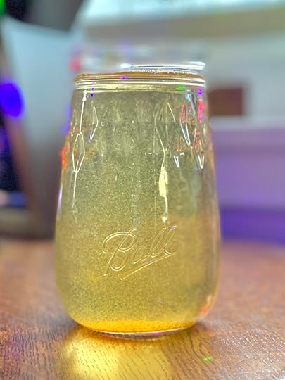 Mulled apple cider syrup in a Ball Flute Jar under a Christmas tree.