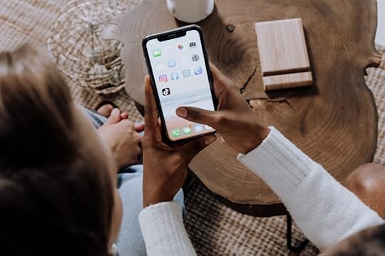 Image: young women looking at a smartphone on which the TikTok app is displayed.
