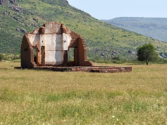 Photograph of the ruins of the chapel at Fort Davis National Historic Site. All that remains is the foundation and most of one wall with its two corners intact. The mountains are in the near background of the photo behind the chapel.