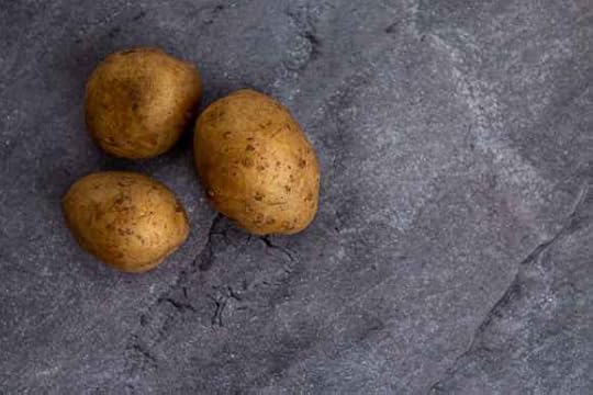 whole uncooked potatoes arranged on gray stone surface