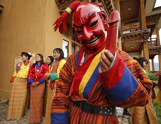 An Atsara, a traditional Bhutanese comedian, holding a wooden carving of a penis