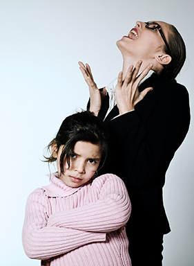 Look beneath the surface of a child's behavior. A mother stands out of sight behind her defiant-looking pre-teen daughter and makes a frustrated face.