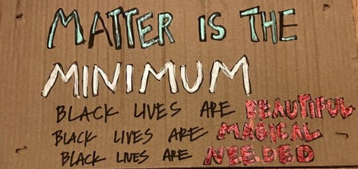 Close up of a brown sign with writing in various colored inks