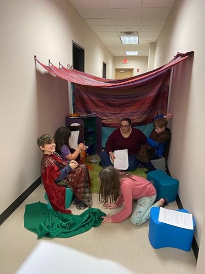 children in costume gathered under a tent in the hallway of the church with teacher Summer Kinard and a cabinet filled with fancy things
