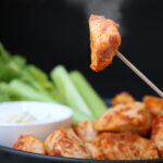 toothpick holding up a chicken bite with steam rising from it.