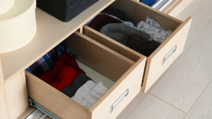 Image of a closet drawer with folded clothes that are organized.