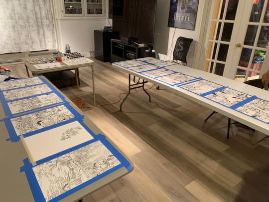 inked comic pages taped to tables in preparation for painting