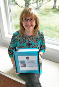 Author Elinor Florence holds binder containing fan mail