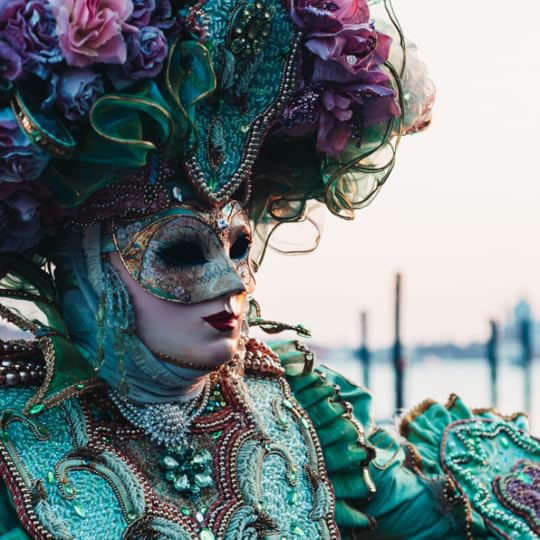 person in a blue and purple mardi gras costume with a flowered headless and mask