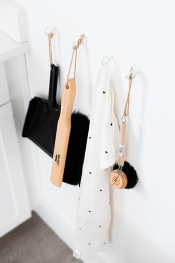 black dust bin and brushes hanging on a white wall in a white kitchen.