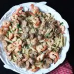 overhead shot of cajun pasta in white bowl on black table.