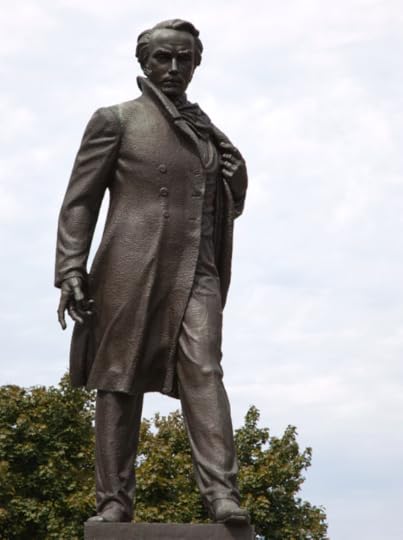Statue of a tall man with a severe expression, left hand on the lapel of his morning coat, right hand by his side, palm open