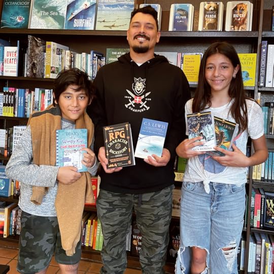 A family at a bookstore, showing off their new books, and the dad is showing off his