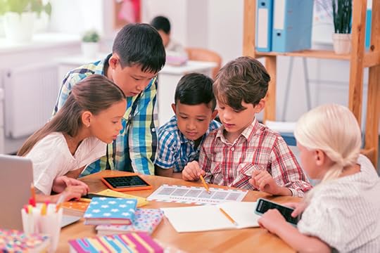 Children in school gather around a workstation to work on a project. When children in a classroom work at different levels, it can be a challenging teaching situation.