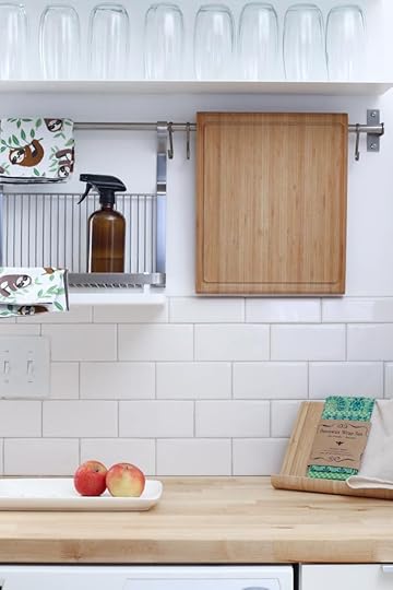 white kitchen with wooden counter and brown spray bottle and red apples