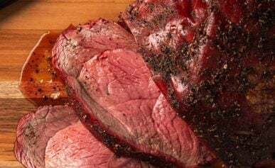 An elk roast, sliced on a cutting board.