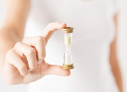 photo of a woman holding a small hourglass style timer. Helping students learn to read in the short window of time they have is a huge reading teacher challenge.