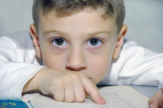 photo of a young boy pointing at a page of a book.